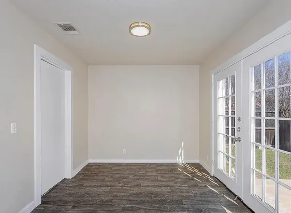 a view of an empty room with wooden floor and a window