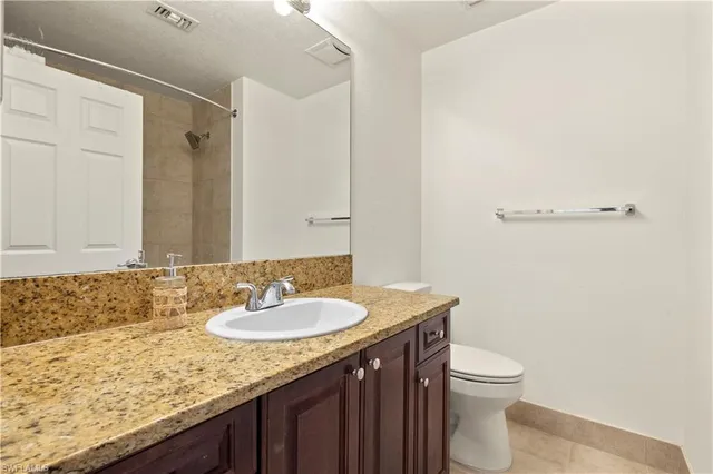 a bathroom with a granite countertop sink a toilet and a shower