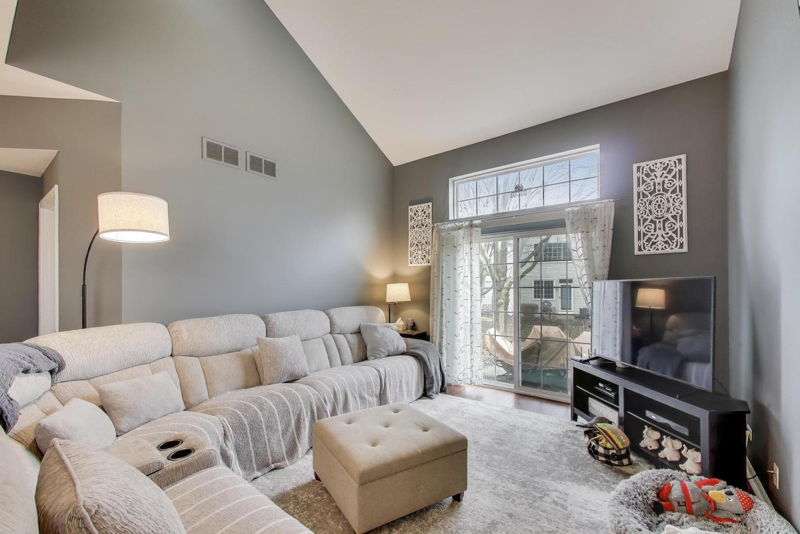 2487 Stonegate Road Algonquin, IL 60102 - Photo 7 of 39 a living room with furniture a flat screen tv and a floor to ceiling window