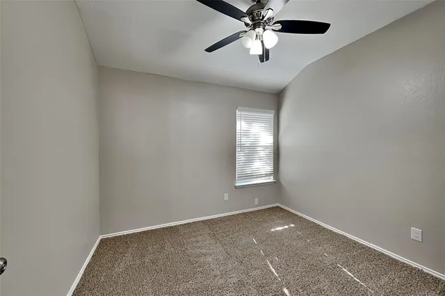 an empty room with windows and chandelier fan