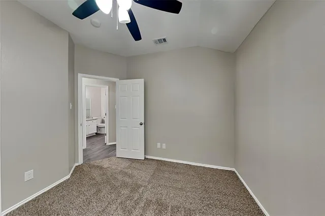 an empty room with a ceiling fan and carpet