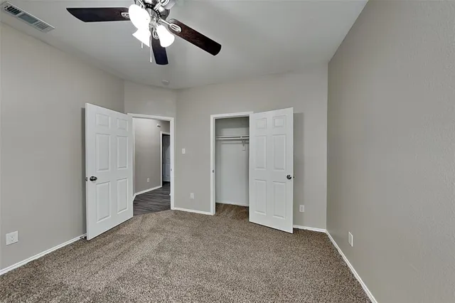 a view of an empty room and chandelier fan