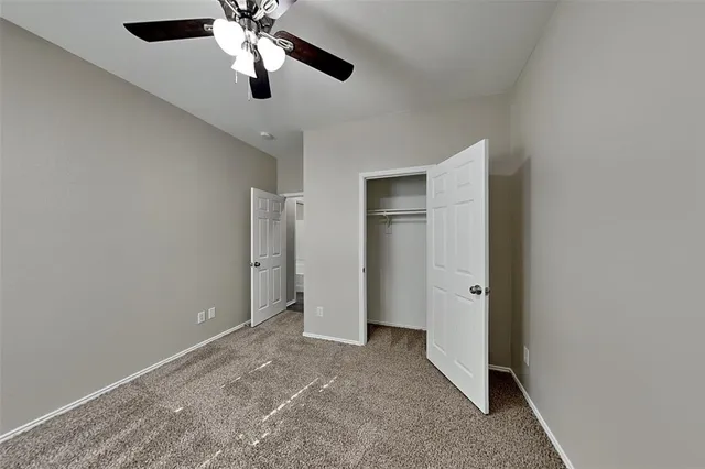 a view of an empty room and chandelier fan