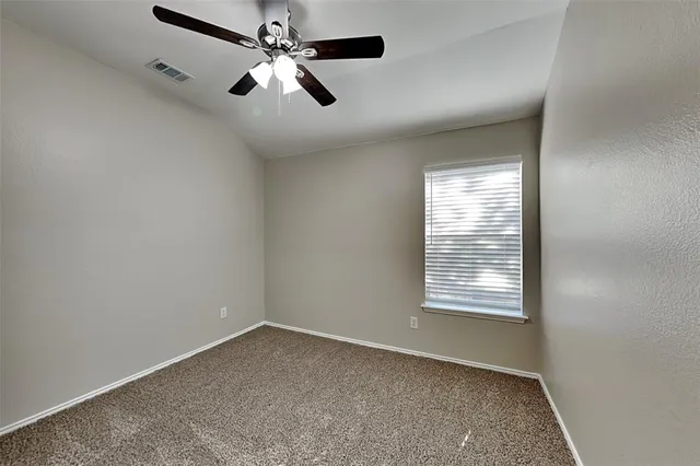 an empty room with windows and fan