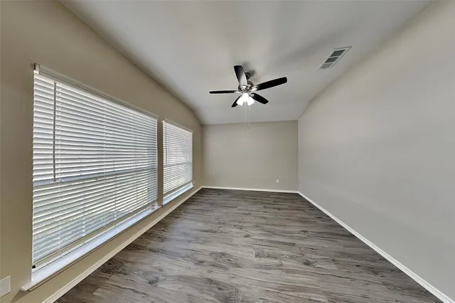 an empty room with wooden floor and windows