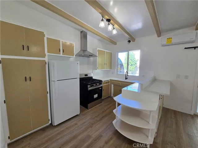 a kitchen with granite countertop a refrigerator a stove a sink dishwasher and a dining table with wooden floor