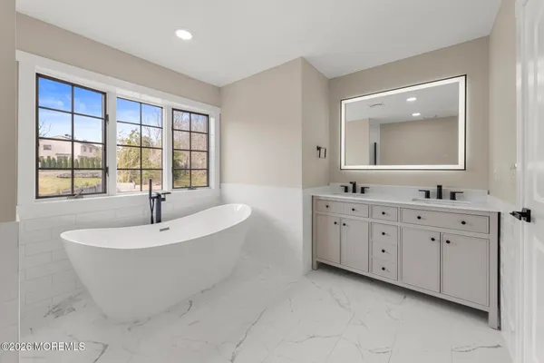 a spacious bathroom with a double vanity sink a mirror and a bathtub