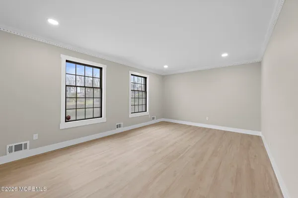 an empty room with wooden floor and windows