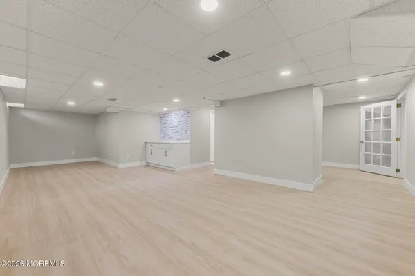 a view of an empty room with wooden floor and windows