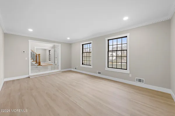 a view of an empty room with a window and wooden floor