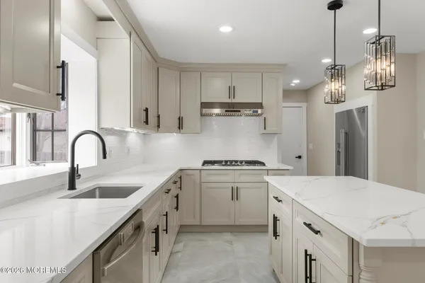 a kitchen with stainless steel appliances granite countertop a sink a stove a refrigerator and island with wooden floor