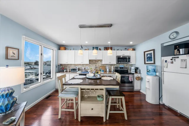 a kitchen with stainless steel appliances kitchen island granite countertop a stove a sink dishwasher a dining table and chairs with wooden floor