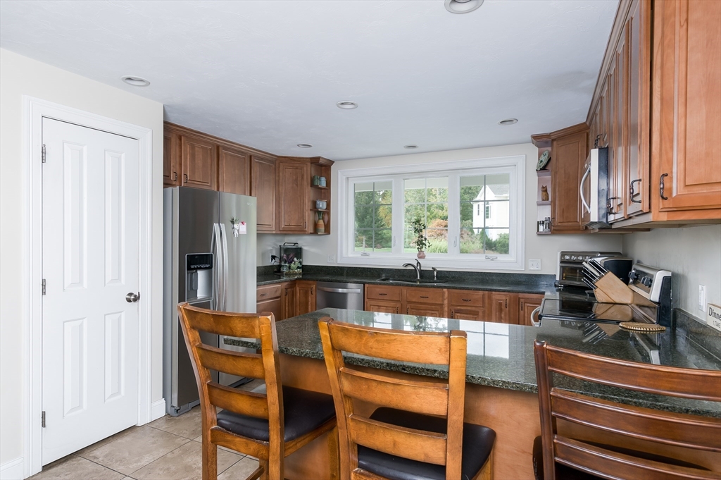 6 Carlson's Way Rutland, MA 01543 - Photo 5 of 34 a kitchen with granite countertop a refrigerator and wooden cabinets