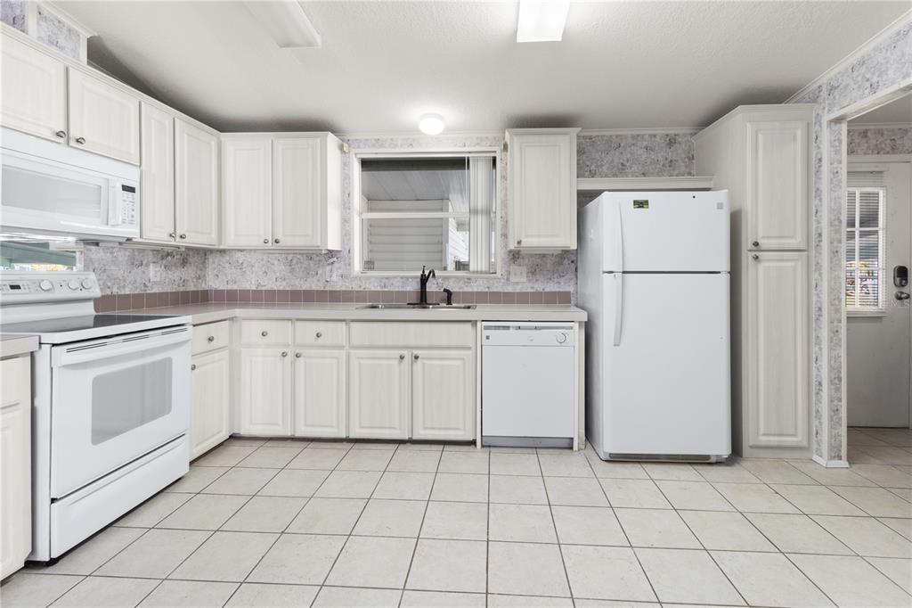 8307 Nancy Lane Ellenton, FL 34222 - Photo 9 of 57 a kitchen with white cabinets a sink and white appliances