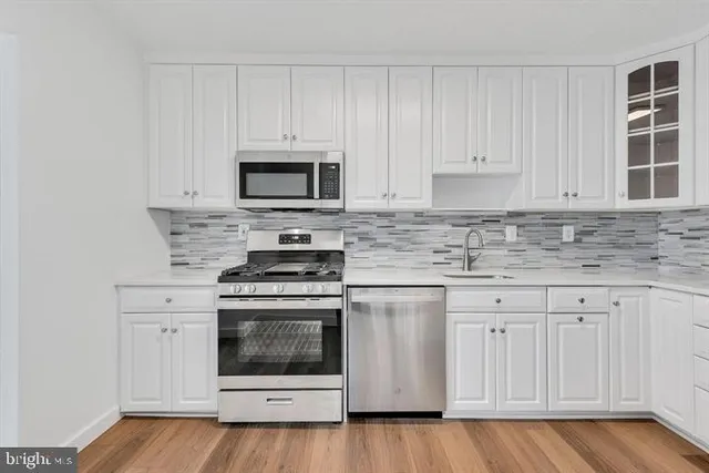 a kitchen with granite countertop white cabinets and stainless steel appliances