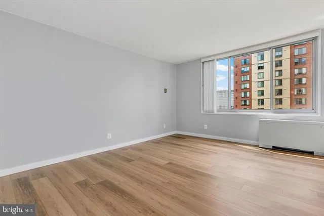 a view of an empty room with wooden floor and a window
