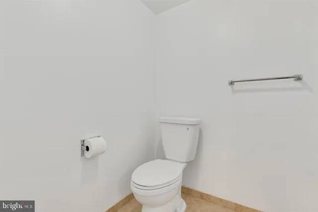 a white toilet sitting next to a white wall