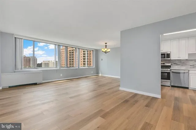 a view of an empty room with a window and wooden floor