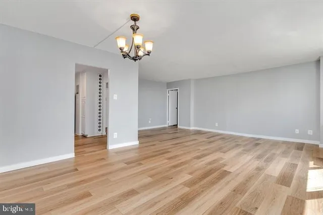 a view of an empty room with wooden floor and a chandelier