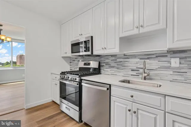 a kitchen with granite countertop white cabinets and stainless steel appliances