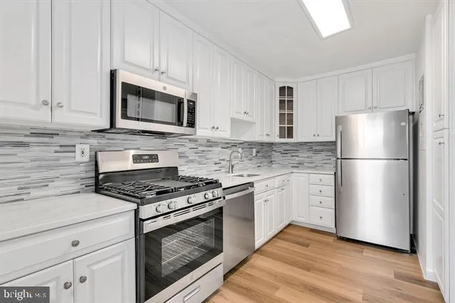 a kitchen with cabinets stainless steel appliances and wooden floor