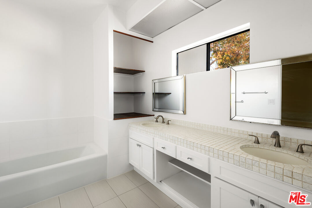 1944 Glendon Avenue, Unit 309 Los Angeles, CA 90025 - Photo 17 of 30 a bathroom with a granite countertop sink a mirror and a bathtub