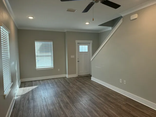an empty room with wooden floor cabinet and windows