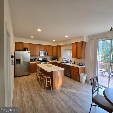 a kitchen with stainless steel appliances granite countertop a stove a sink dishwasher a refrigerator white cabinets and wooden floor