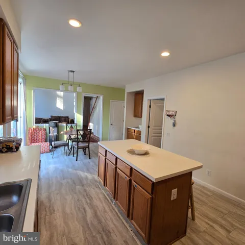 a living room with stainless steel appliances granite countertop furniture wooden floor and a sink
