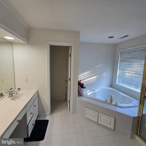 a spacious bathroom with a tub sink and mirror