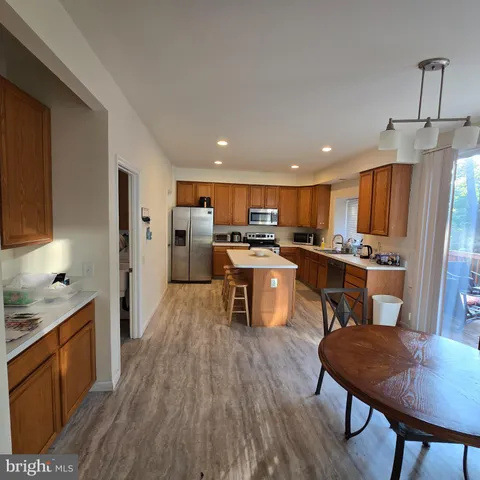 a kitchen with stainless steel appliances kitchen island granite countertop wooden floors and wooden cabinets