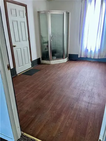 an empty room with wooden floor and a mirror