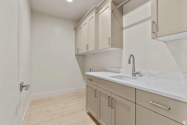 2955 East Rimrunner Drive St. George, UT 84790 - Photo 23 of 35 Laundry area featuring light wood-finish flooring, extensive cabinetry with brushed nickel hardware, and a white countertop with an integrated sink and gooseneck faucet