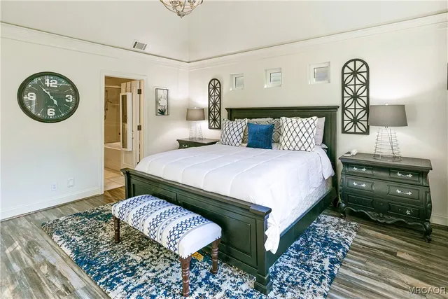 a bedroom with a bed a clock on dresser and a table