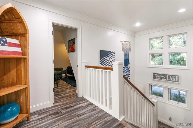 a view of a hallway to a livingroom with wooden floor and windows