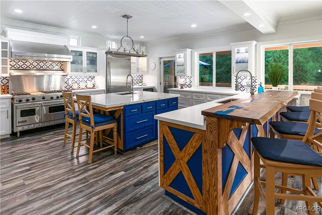 a kitchen with stainless steel appliances granite countertop a stove a sink dishwasher a dining table and chairs with wooden floor