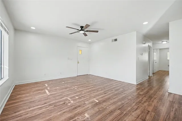 a view of empty room with wooden floor and fan