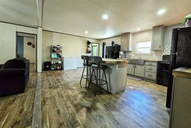 a kitchen with stainless steel appliances granite countertop a refrigerator a stove top oven a sink dishwasher and white cabinets with wooden floor
