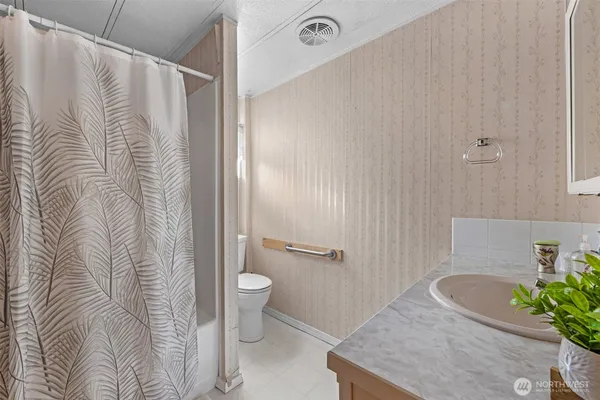 a bathroom with a granite countertop sink a toilet and shower