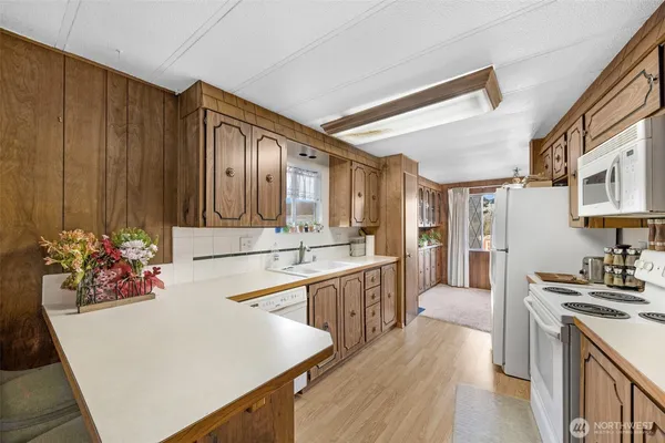 a large white kitchen with wooden floor and a sink