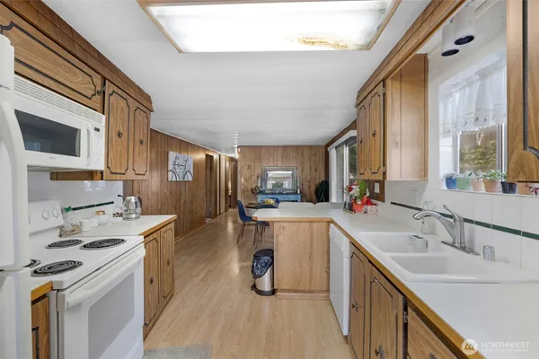 a kitchen with a sink a counter top space stainless steel appliances cabinets and a large window