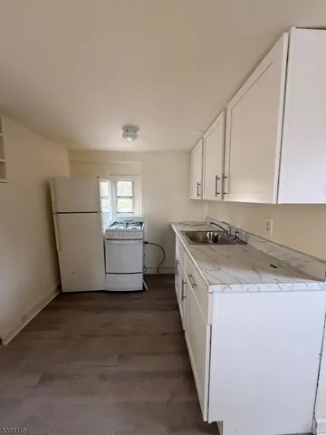 a kitchen with a sink a stove a refrigerator and white cabinets