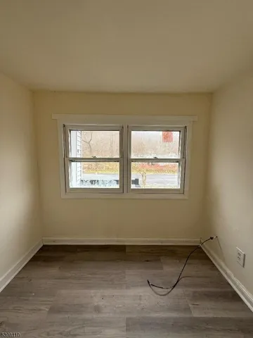 a view of an empty room with wooden floor and window
