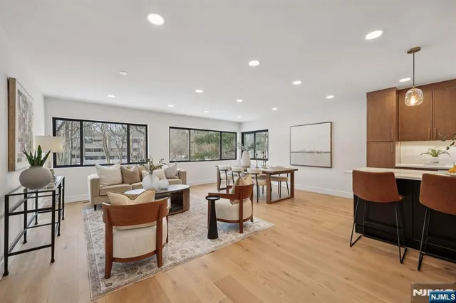 a living room with couches a coffee table and kitchen view with wooden floor
