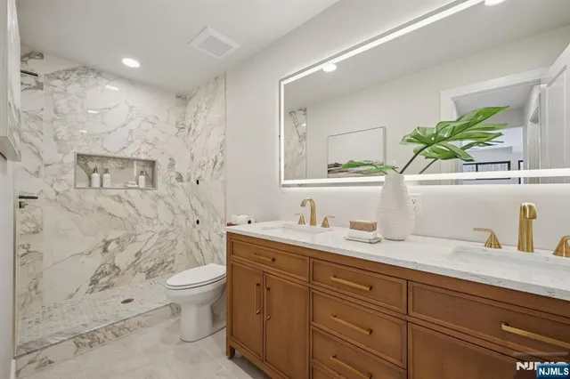 a bathroom with a granite countertop toilet sink and mirror