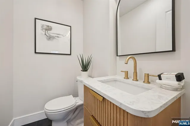 a bathroom with a granite countertop sink and a toilet