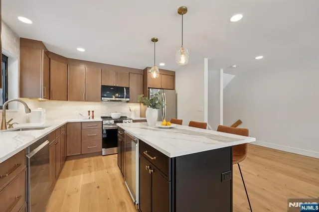 a kitchen with a stove a sink a kitchen island with chairs and wooden cabinets