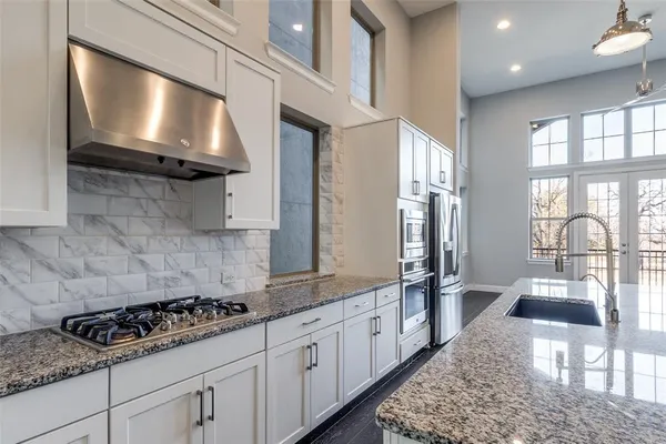 a kitchen with stainless steel appliances granite countertop a refrigerator a stove and a sink with granite countertops