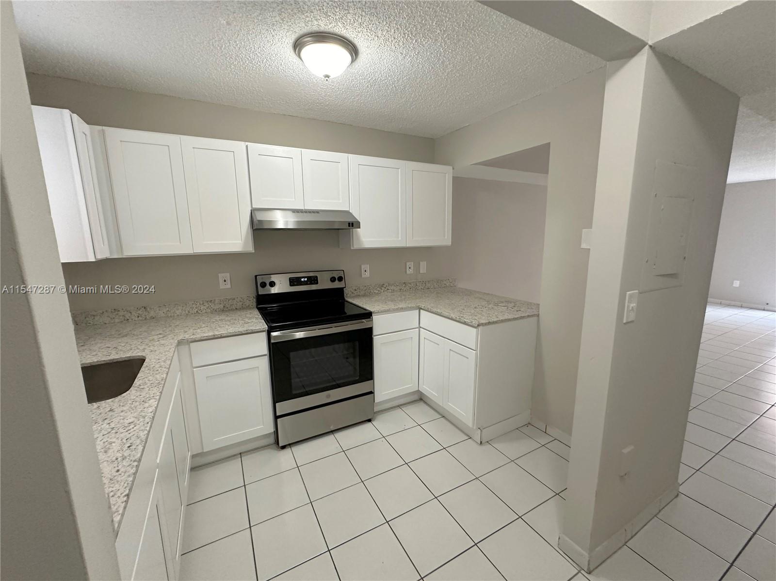 3051 West 76th Street, Unit D211 Hialeah, FL 33018 - Photo 6 of 22 a kitchen with white cabinets a sink a stove and a refrigerator