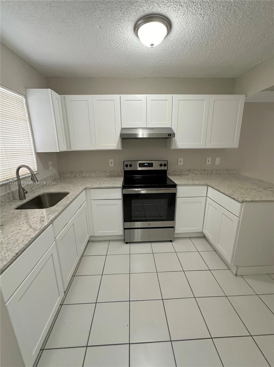 3051 West 76th Street, Unit D211 Hialeah, FL 33018 - Photo 7 of 22 a kitchen with stainless steel appliances a sink a stove a microwave and cabinets